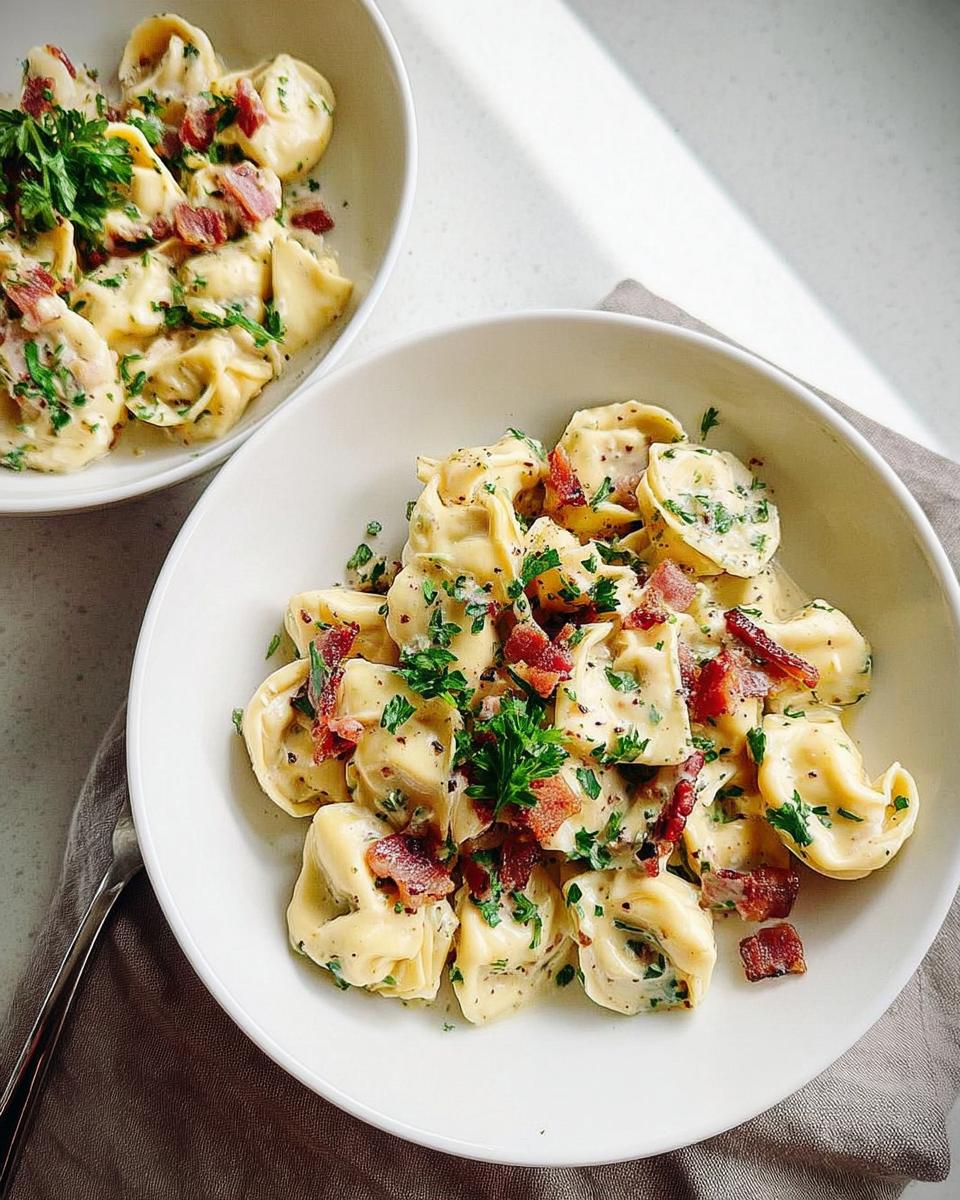 Close-up of creamy tortellini pasta with crispy bacon bits and fresh parsley. A perfect 5-Ingredient Pasta Recipe.