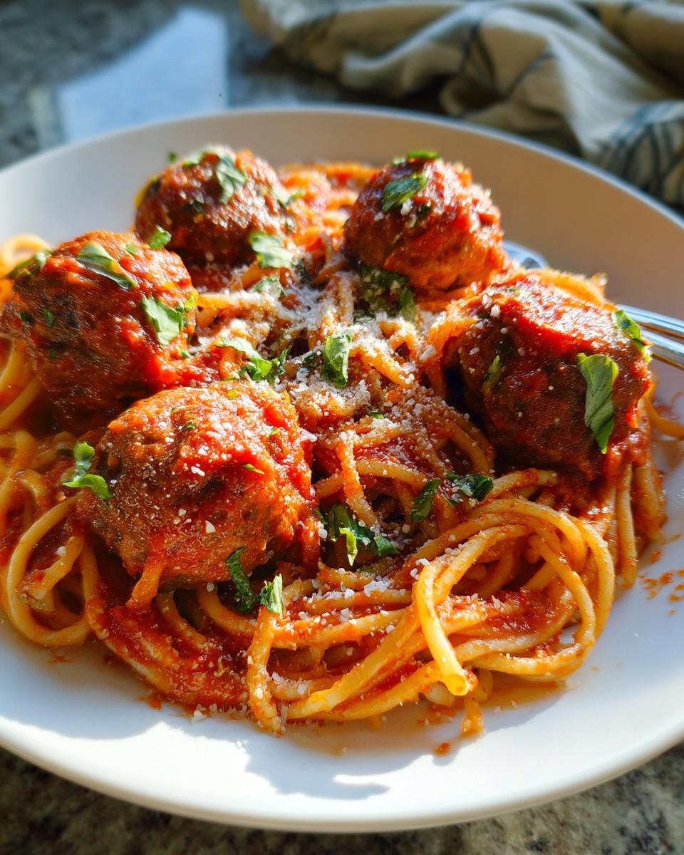 A close-up of The Best Italian Spaghetti and Meatballs topped with grated cheese and parsley.