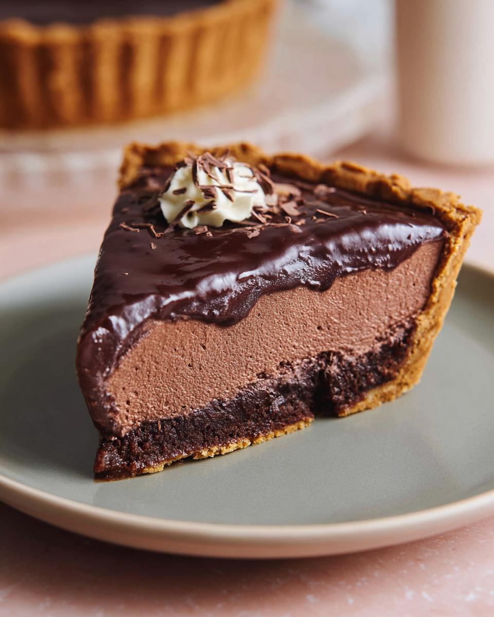 A slice of rich chocolate tart, topped with whipped cream and chocolate shavings, part of the Best Thanksgiving Desserts 2025.