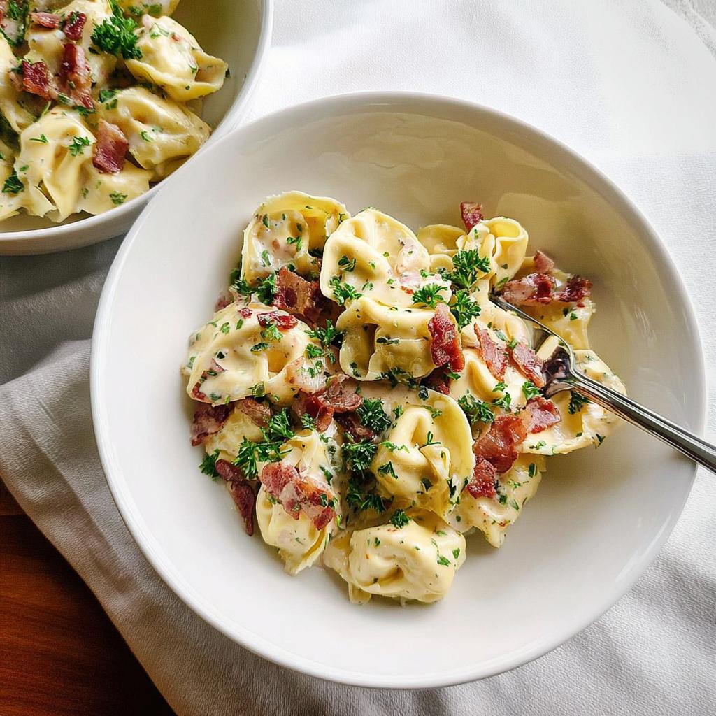 Close-up of a bowl of creamy tortellini pasta with crispy bacon bits and fresh parsley, part of 5-Ingredient Pasta Recipes.