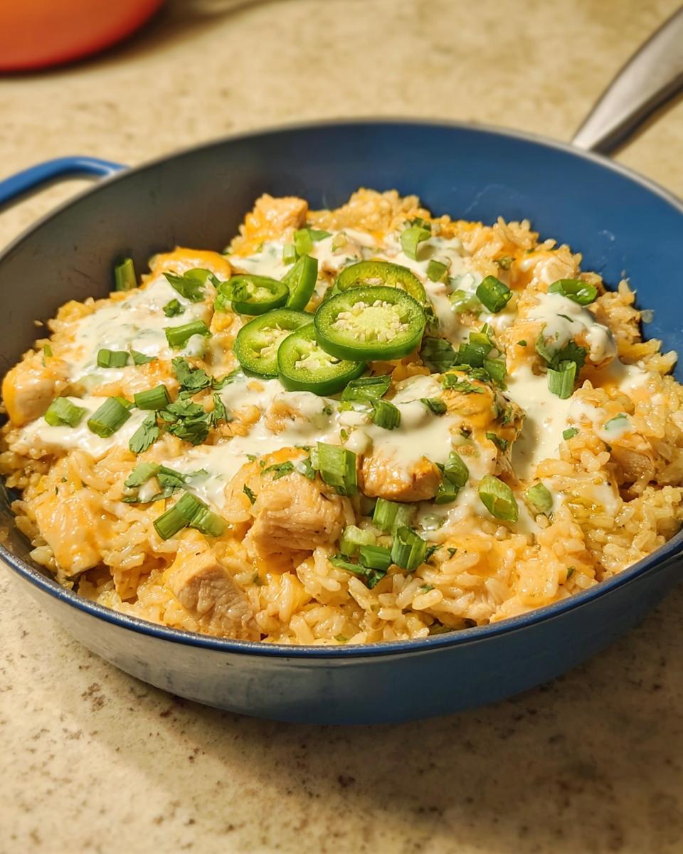 A close-up of a creamy chicken and rice dish, topped with sliced jalapenos, cilantro, and green onions, perfect for dinner recipes.