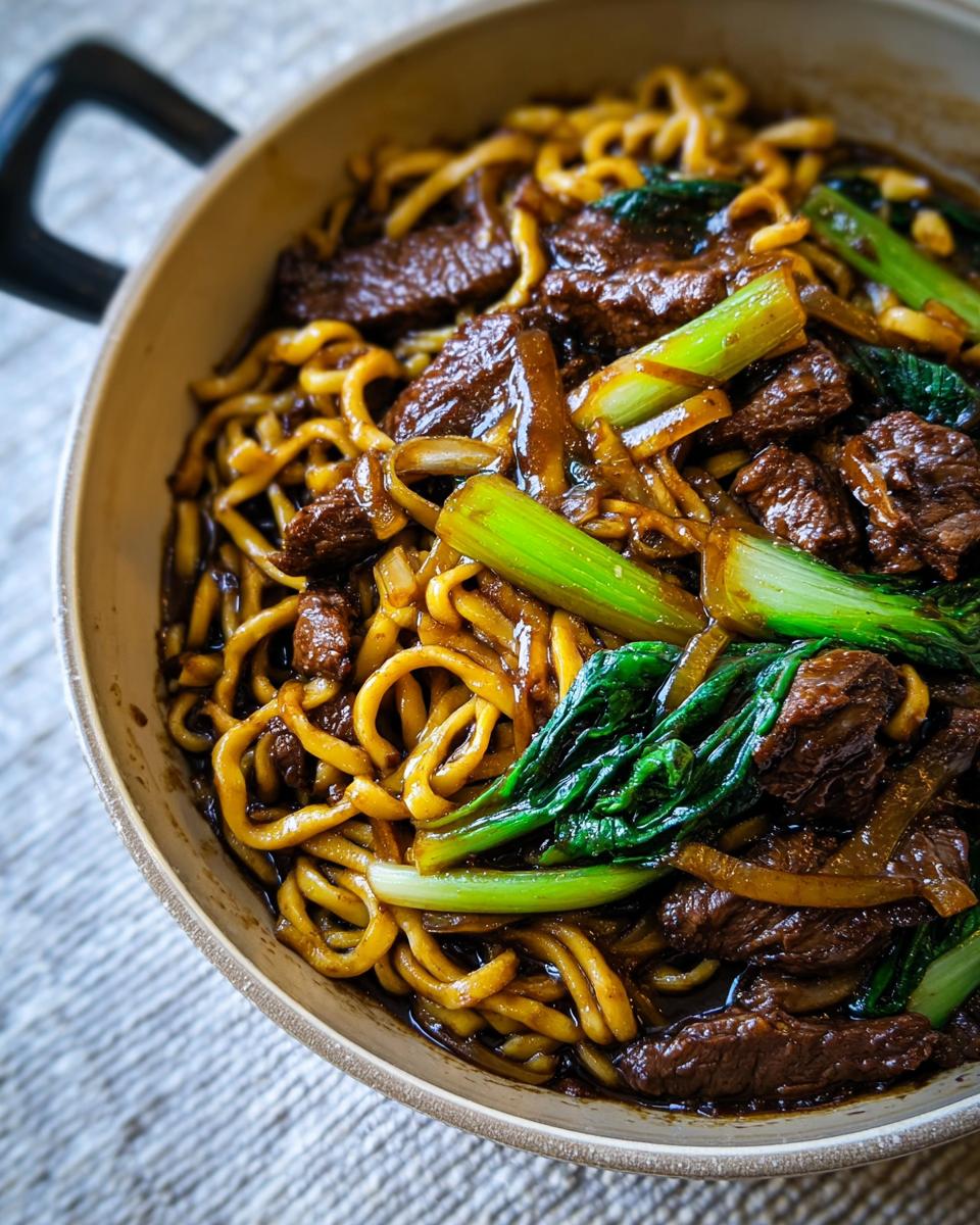 Close-up of a bowl of easy dinner recipes with beef, bok choy, and noodles in a savory sauce.