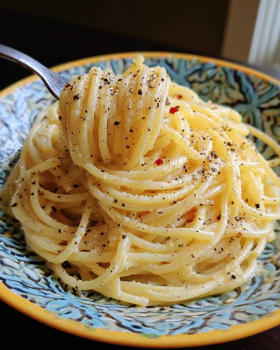 A fork twirling creamy spaghetti, seasoned with black pepper and red pepper flakes, a perfect foolproof dinner idea.