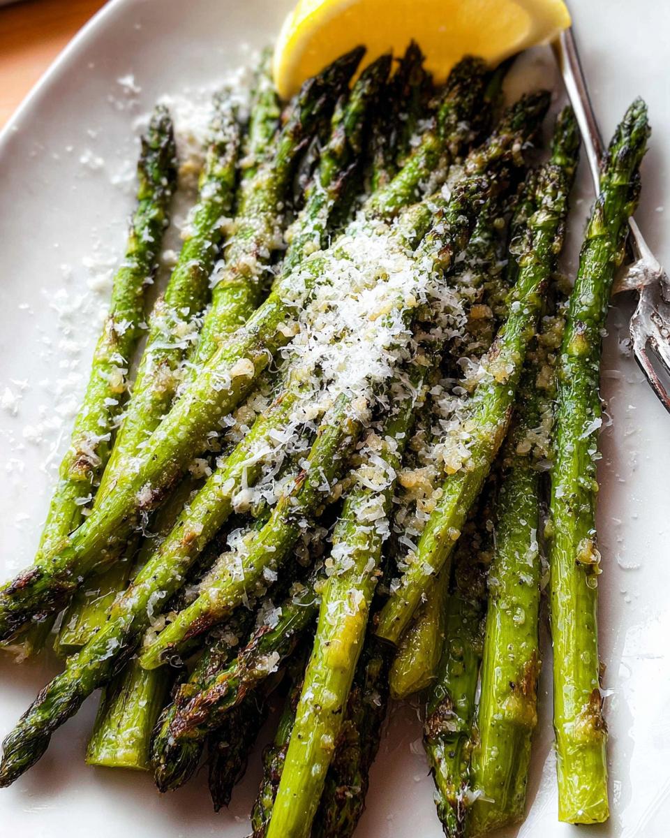 Close-up of perfectly Roasted Asparagus with Parmesan cheese sprinkled on top, served with a lemon wedge.