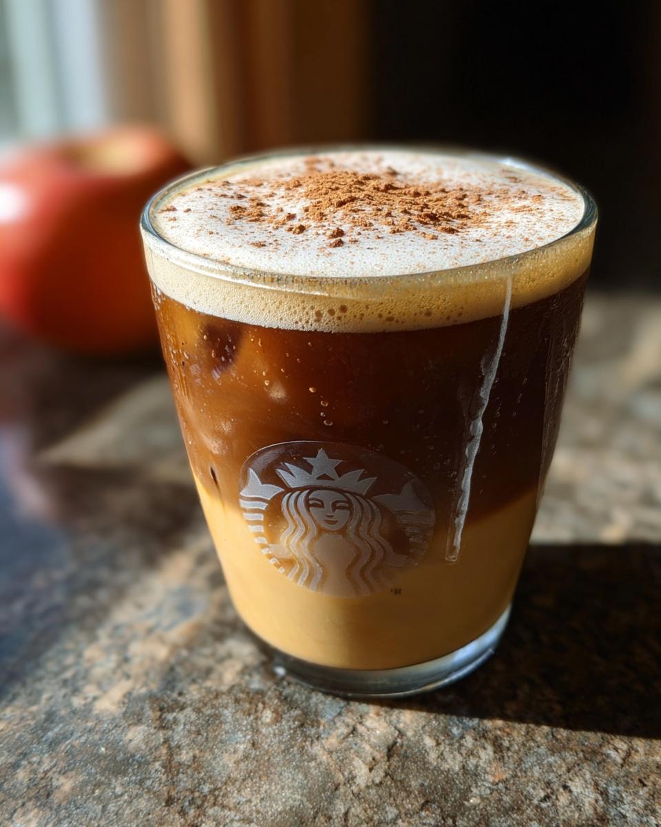 A Starbucks Apple Crisp Macchiato drink with layers of espresso, milk, and cinnamon topping.