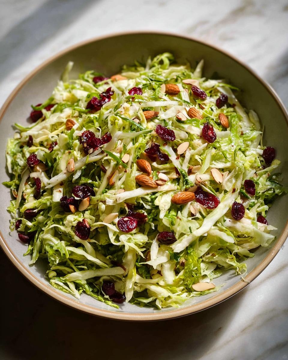 A vibrant bowl of Thanksgiving salad featuring shredded cabbage, dried cranberries, and sliced almonds.