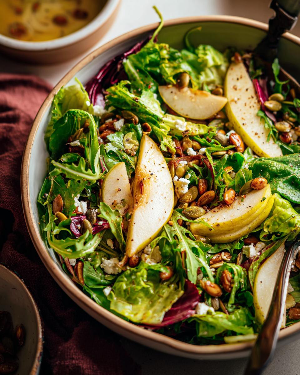 A vibrant Thanksgiving salad recipe featuring fresh greens, sliced pears, crumbled feta, and mixed seeds.
