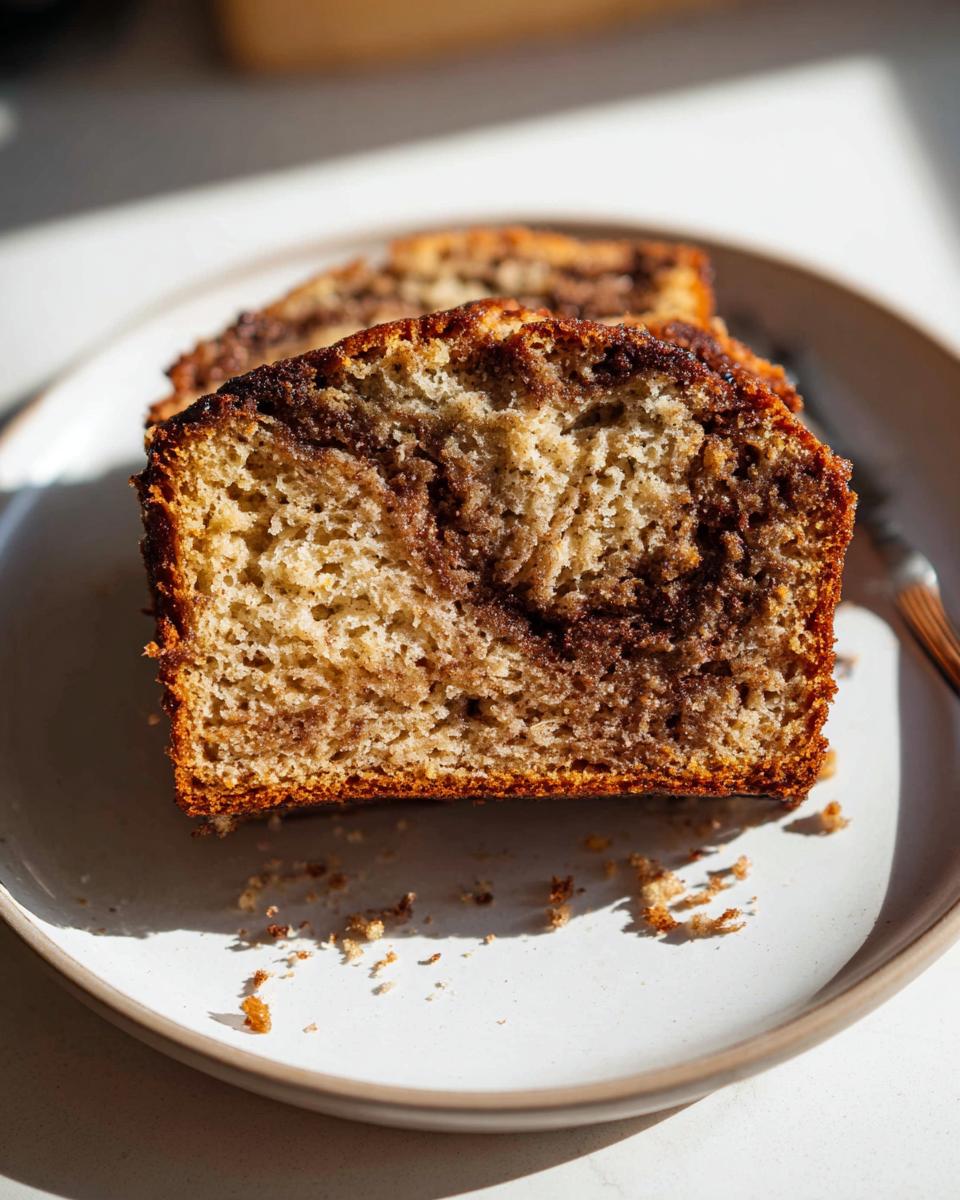Close-up of a moist slice of Cinnamon Swirl Banana Bread showing the rich brown cinnamon swirl pattern inside.