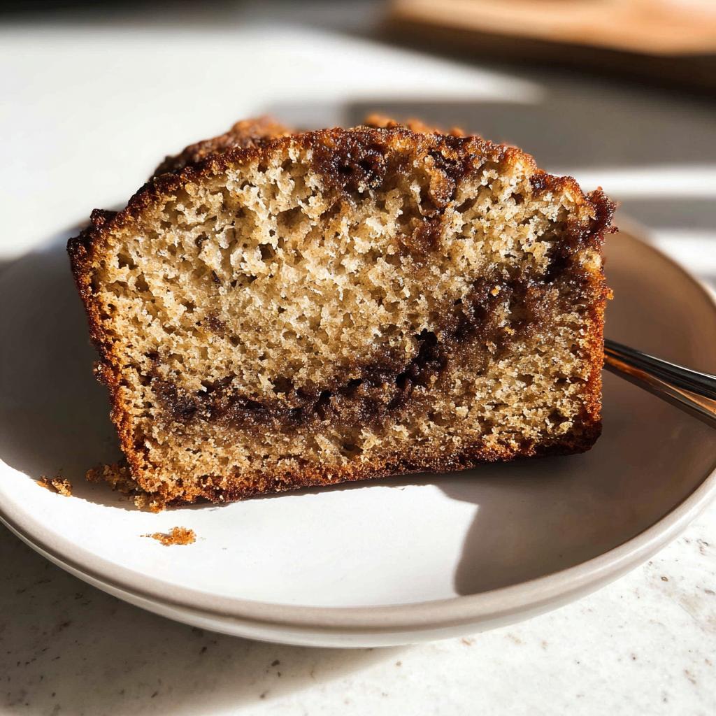 Close-up of a moist slice of Cinnamon Swirl Banana Bread showing the rich, dark swirl filling.