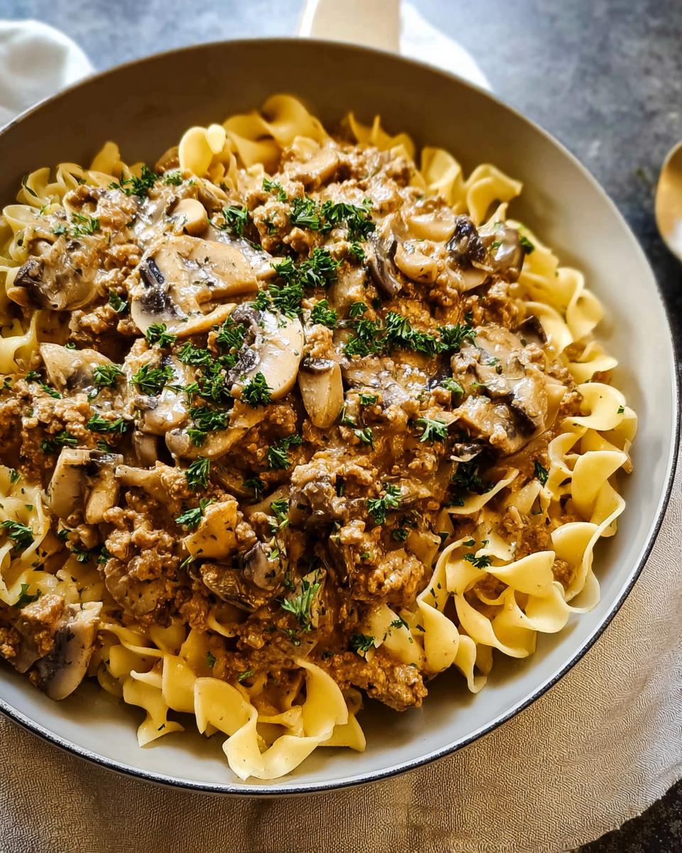 A close-up of Creamy Turkey Stroganoff served over wide egg noodles, topped with mushrooms and fresh parsley.