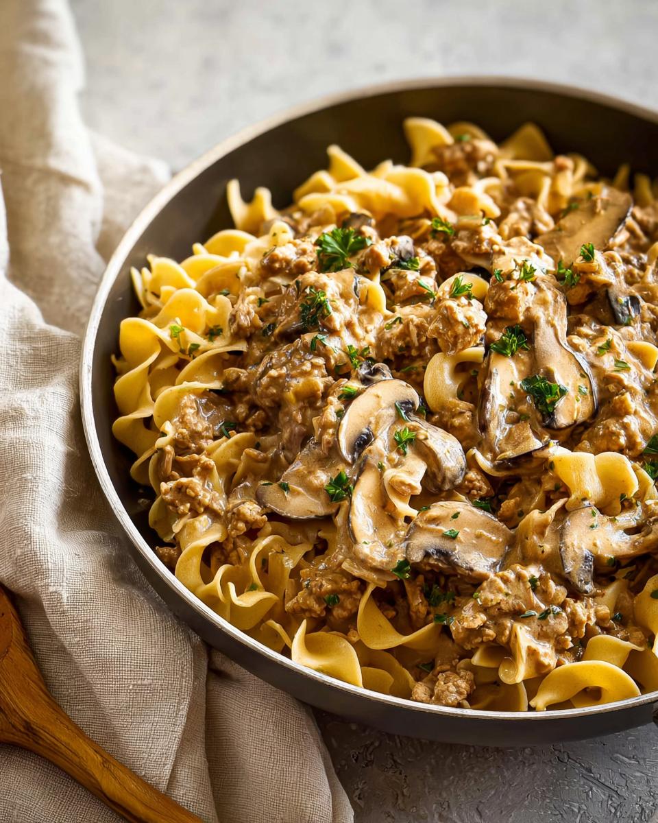Close-up of Creamy Turkey Stroganoff served over wide egg noodles, topped with mushrooms and parsley.