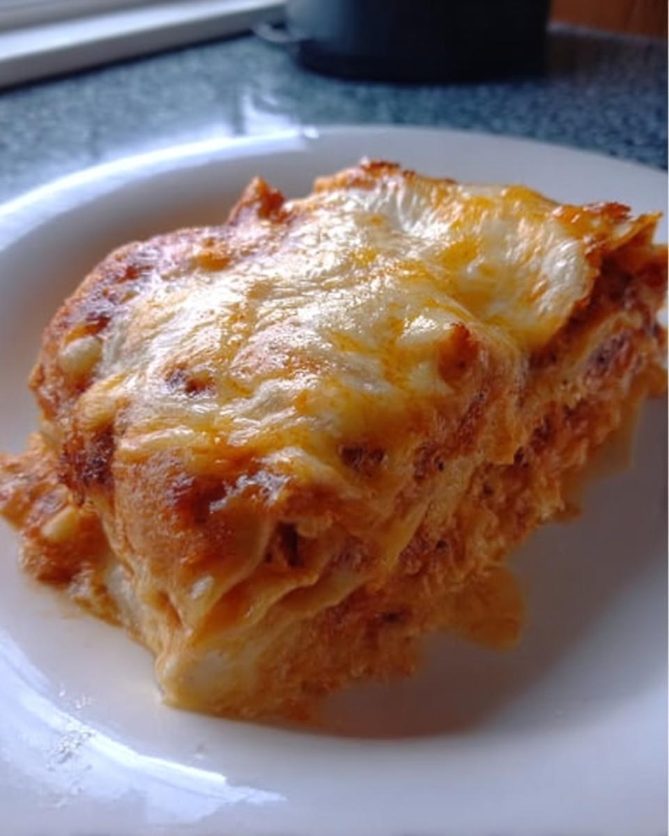 A close-up of a generous slice of Extra Cheesy Four Cheese Lasagna with a bubbly, golden-brown cheese topping.