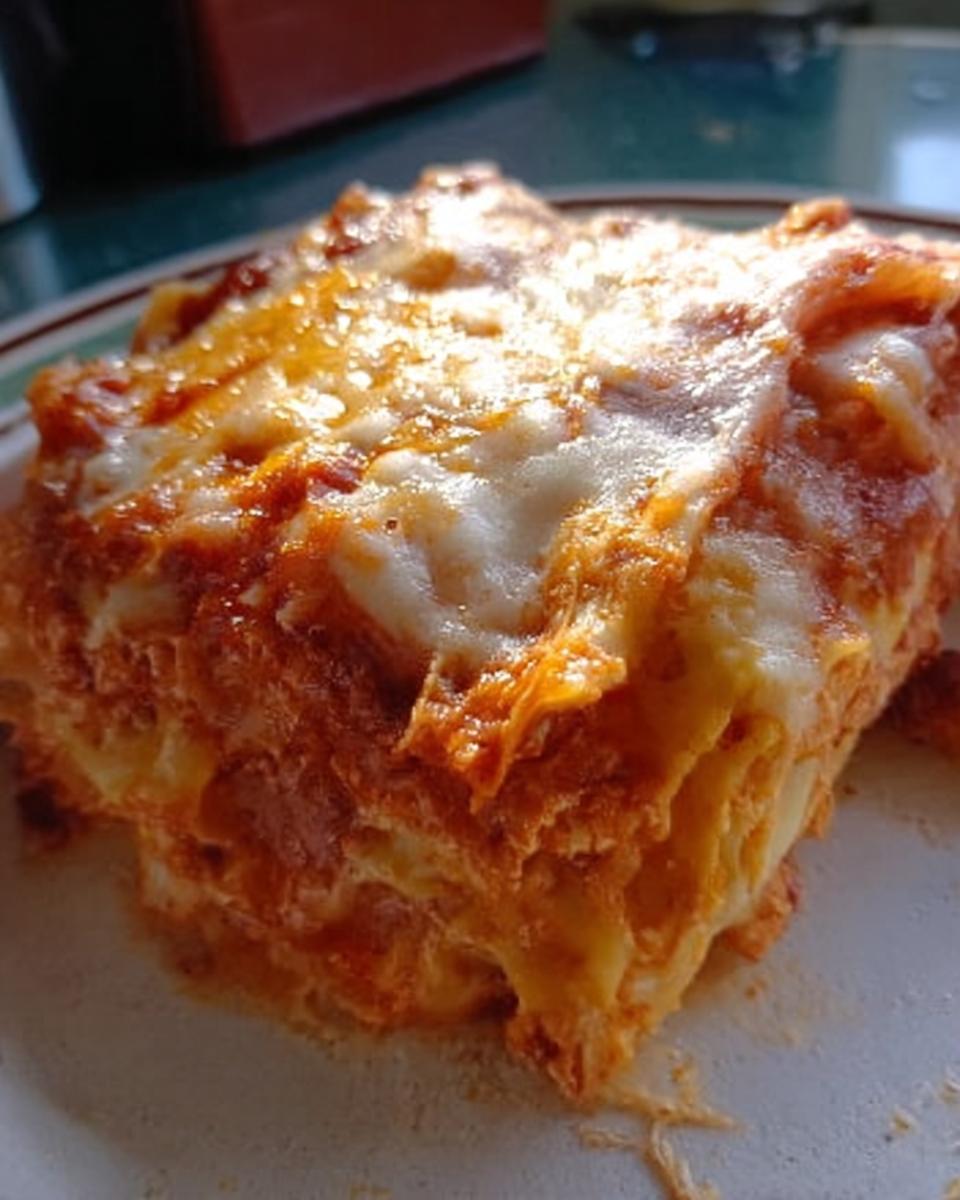 Close-up of a generous slice of Extra Cheesy Four Cheese Lasagna showing layers and a bubbly, melted cheese topping.