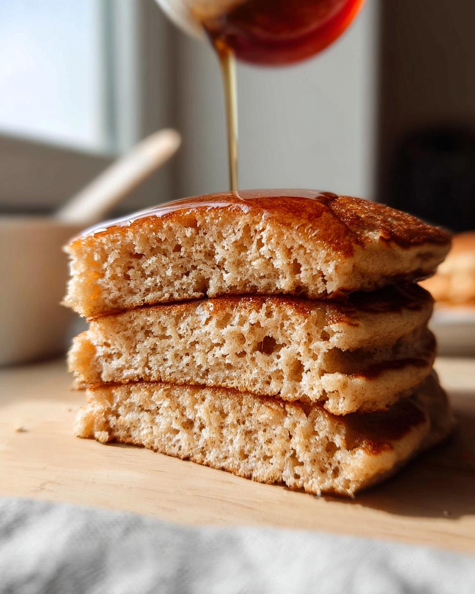 Close-up showing the airy, fluffy interior texture of three stacked Fluffy Pancakes as syrup is poured on top.
