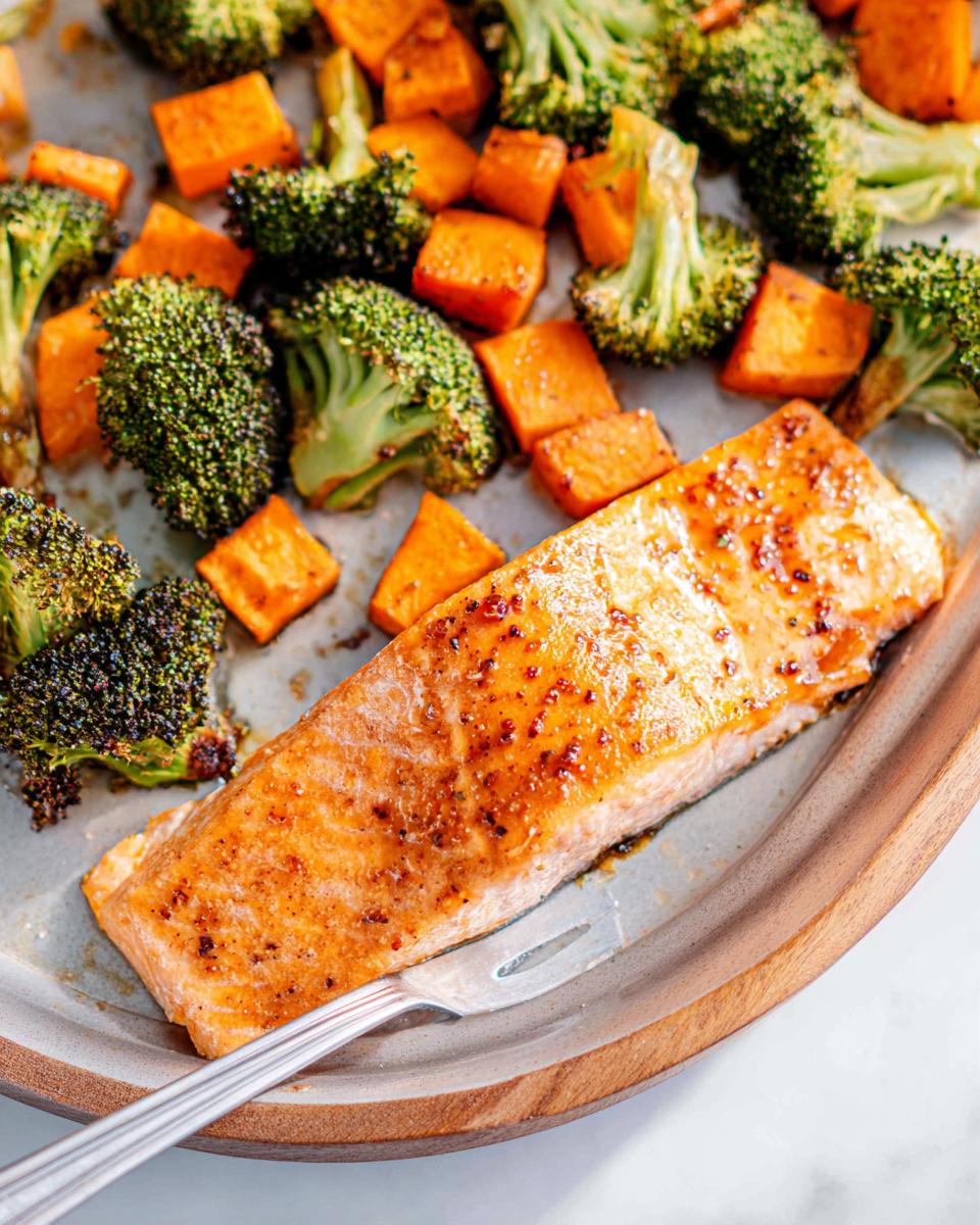 A perfectly cooked fillet of Maple Dijon Salmon Sheet Pan Dinner served with roasted broccoli and sweet potatoes.