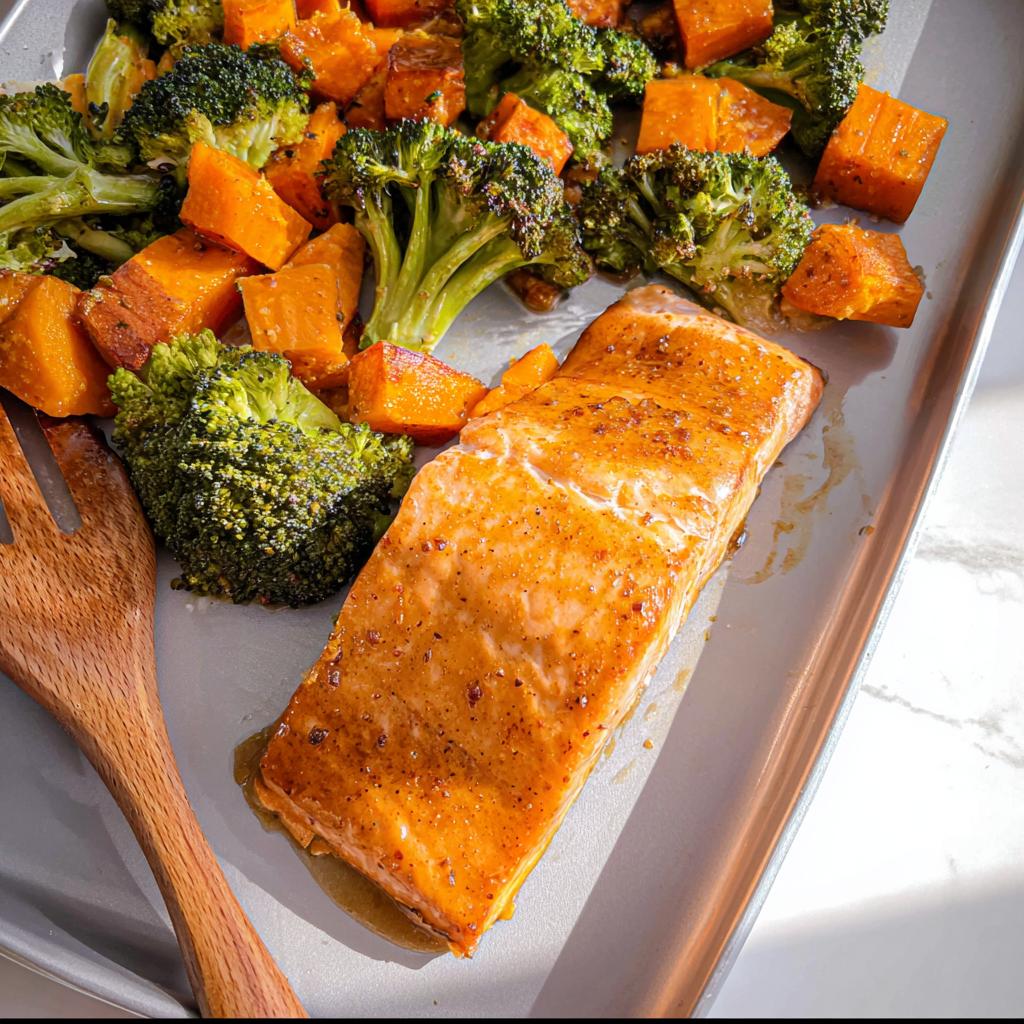 Close-up of a glazed salmon fillet next to roasted broccoli and sweet potatoes on a sheet pan for the Maple Dijon Salmon Sheet Pan Dinner.