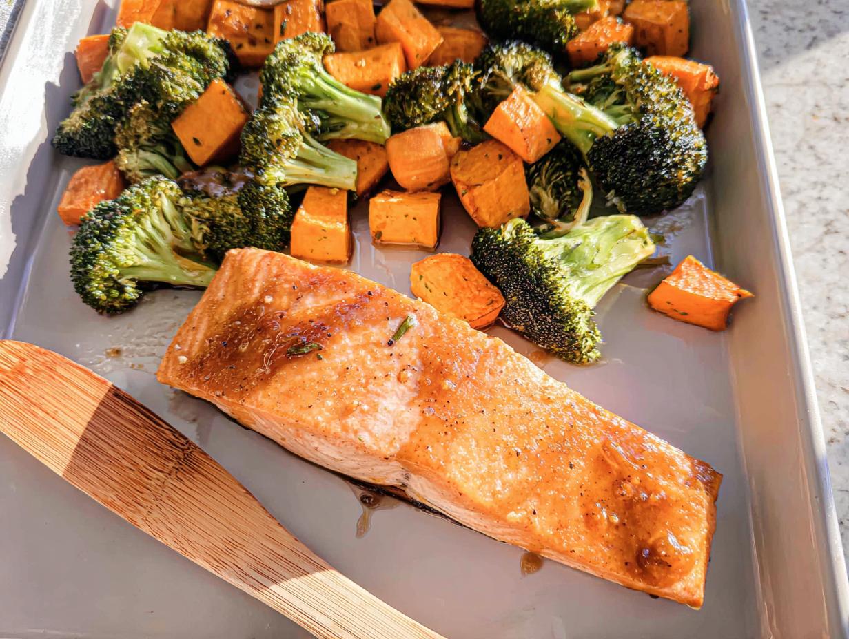 Glazed salmon fillet next to roasted broccoli and sweet potatoes on a sheet pan for Maple Dijon Salmon Sheet Pan Dinner.
