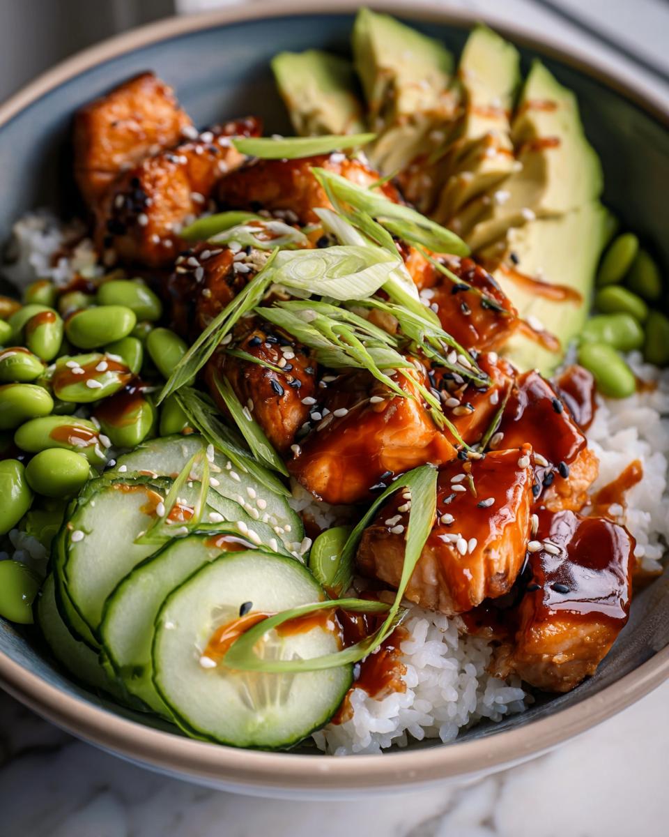 Close-up of a Teriyaki Glazed Salmon Rice Bowls featuring glazed salmon, rice, edamame, cucumber, and avocado.