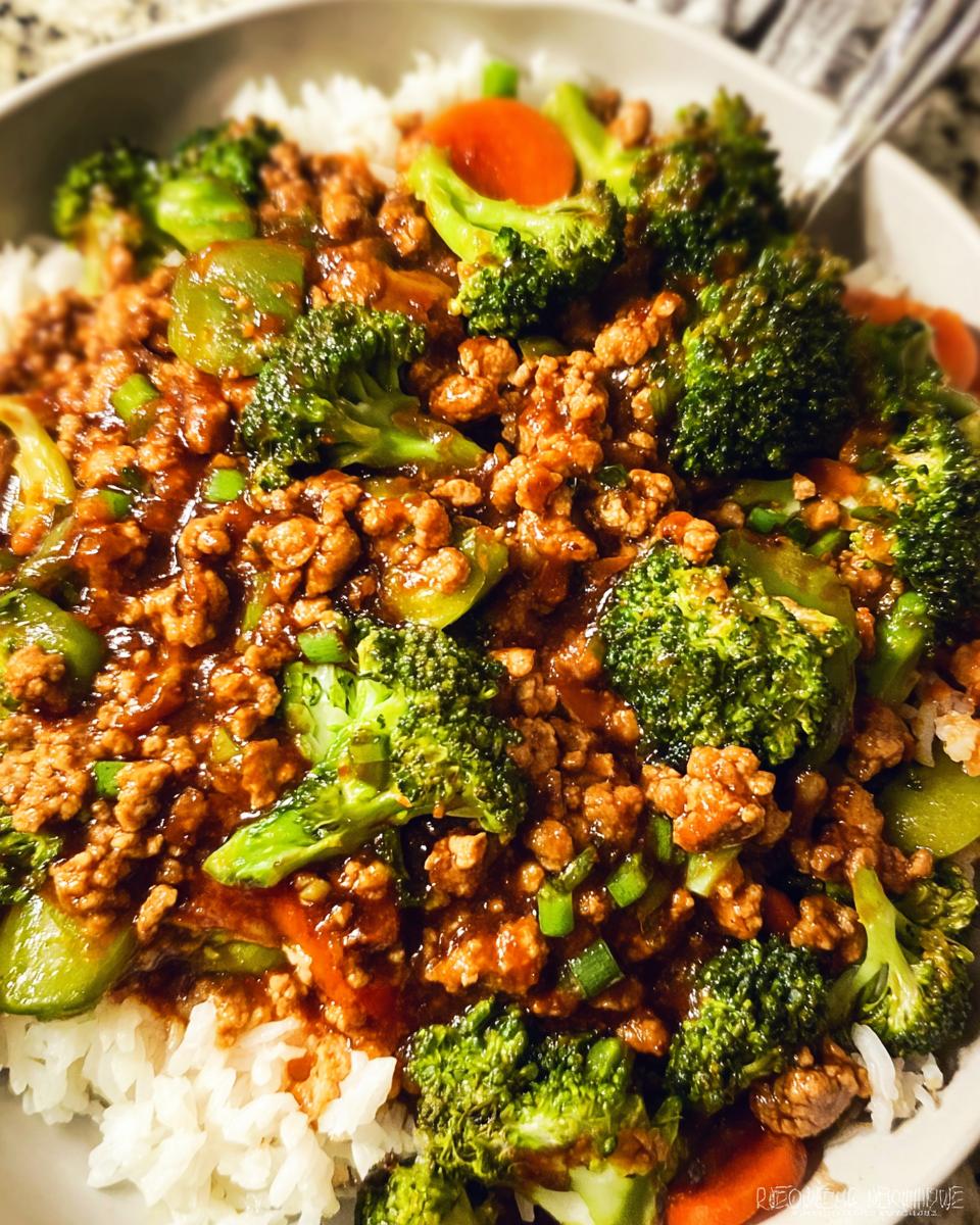 A close-up of a Teriyaki Ground Turkey Bowl served over white rice, featuring ground turkey, bright green broccoli florets, and carrots in a savory sauce.