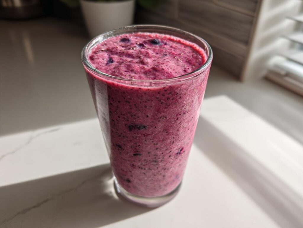 A tall glass filled with a thick, vibrant purple berry smoothie, perfect for when you Build Your Healthy Smoothie.