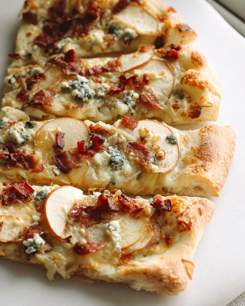 Close-up of a slice of 10-ingredient pear and bacon pizza with blue cheese and crispy bacon.