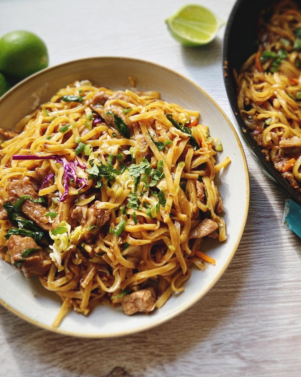 Delicious and easy dinner recipe featuring savory noodles with meat, vegetables, and lime wedges.