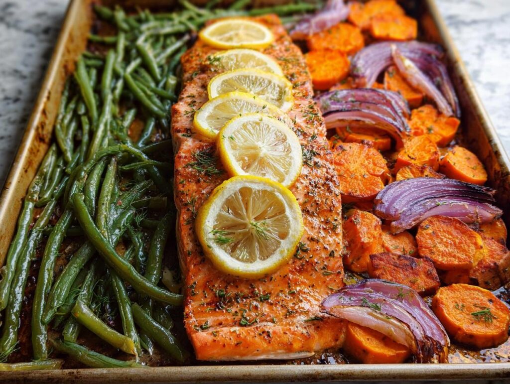 A delicious sheet pan meal prep featuring a salmon fillet with lemon slices, green beans, sweet potatoes, and red onion.