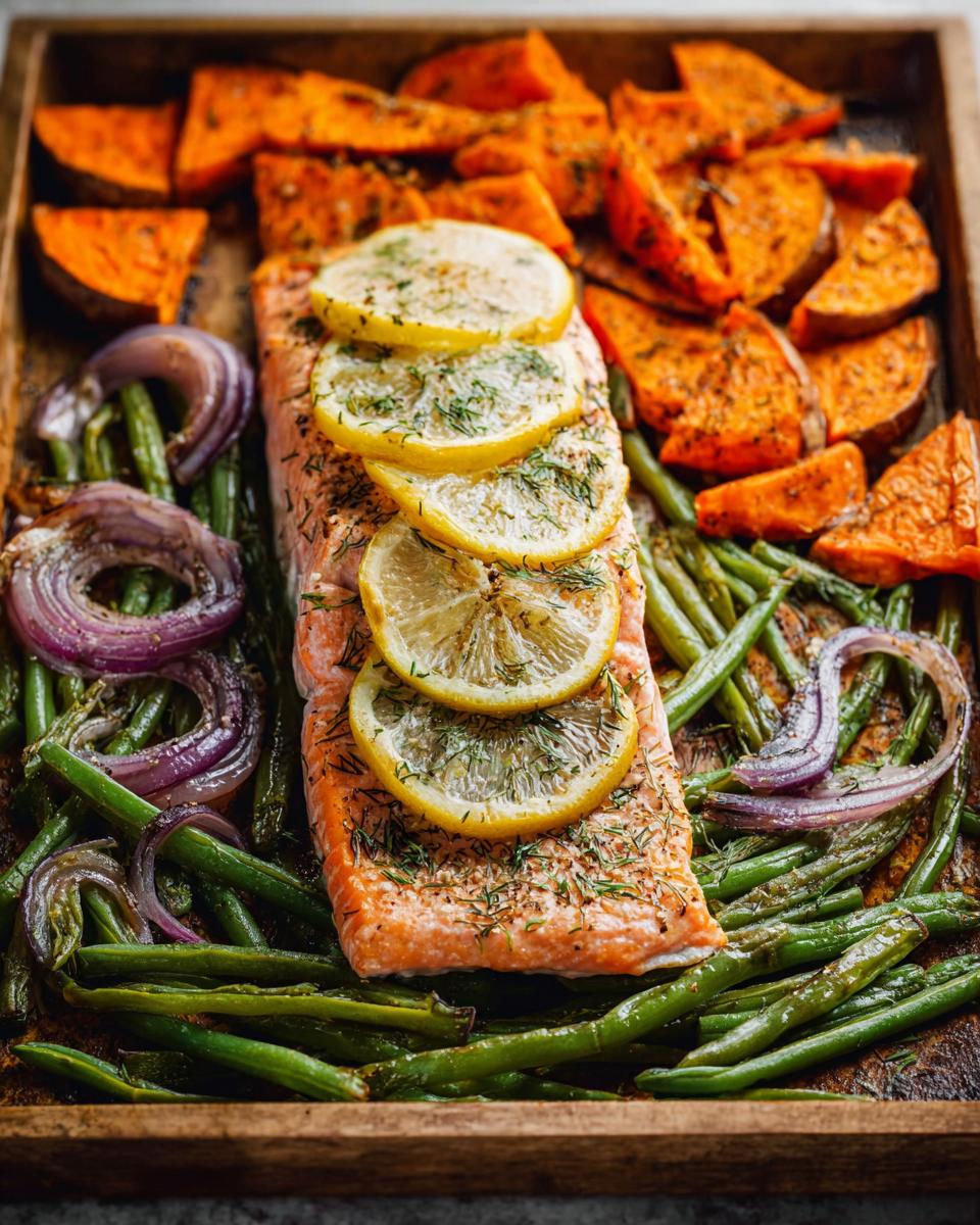A delicious sheet pan meal featuring a salmon fillet topped with lemon slices and dill, surrounded by roasted sweet potato wedges and green beans.