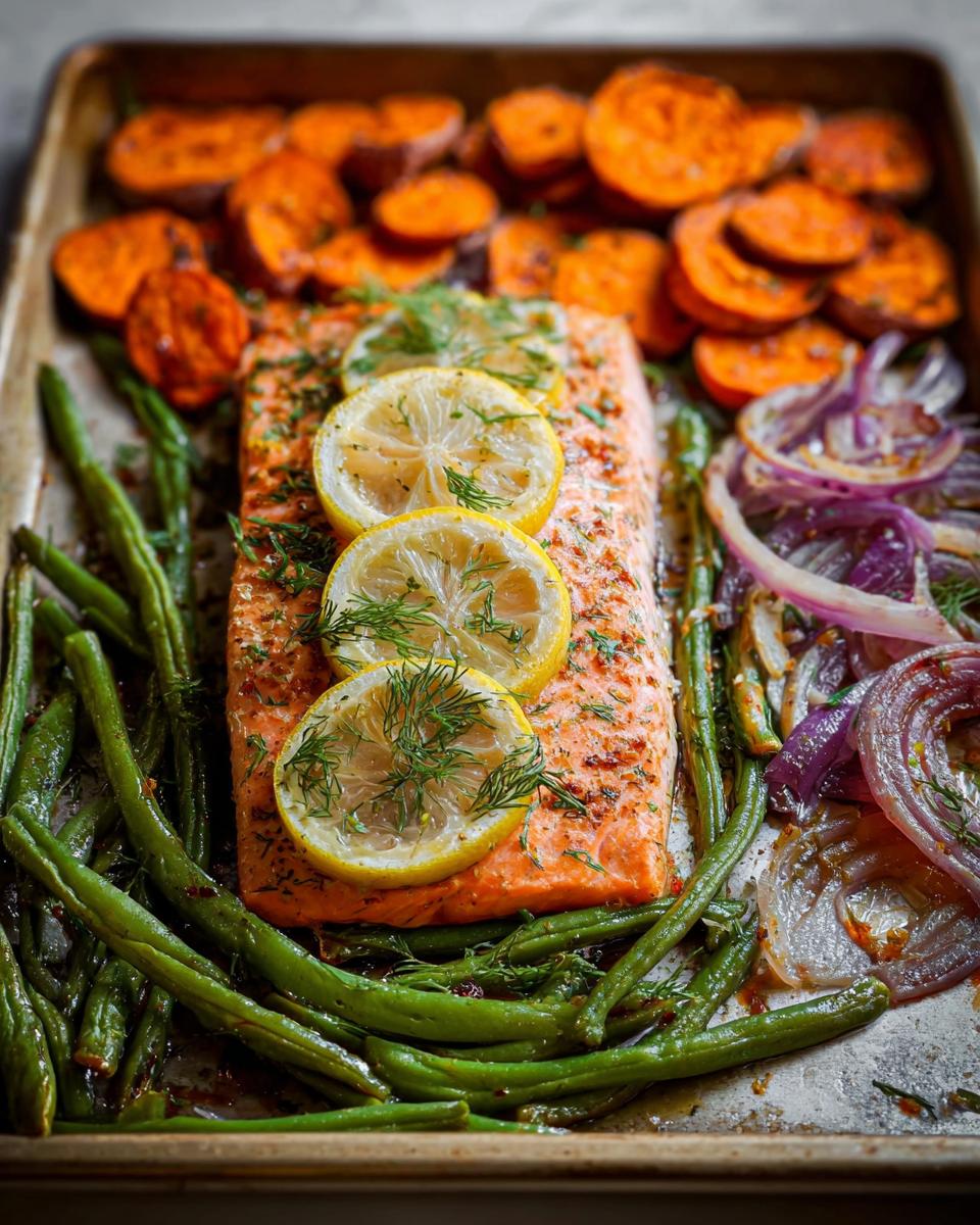 A close-up of a delicious sheet pan meal prep featuring a salmon fillet, roasted sweet potato slices, green beans, and red onion.