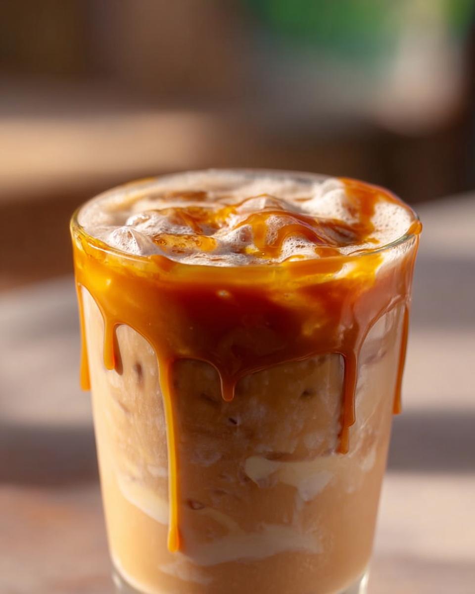 Close-up of an iced caramel macchiato with caramel drizzle, a Starbucks drink recipe.