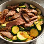 A close-up of a bowl filled with sliced grilled steak and tender zucchini rounds, a perfect Cozy Grilled Steak Bowl with Zucchini.