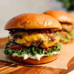 Close-up of a juicy Crack Burger with double patties, melted cheddar cheese, lettuce, tomato, and pickles.