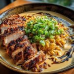 A close-up of a bowl of Creamy Garlic Chicken Ramen, featuring sliced grilled chicken, ramen noodles, and chopped green onions.