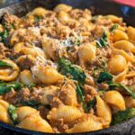 Close-up of Creamy High Protein Beef Pasta with spinach and cheese in a cast iron skillet.
