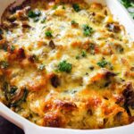 A close-up of a bubbling Creamy Low Carb Chicken Casserole topped with melted cheese and fresh parsley.