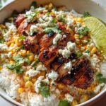 A close-up of an Easy Street Corn Chicken Bowl featuring grilled chicken, corn, rice, crumbled cheese, cilantro, and a lime wedge.