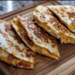 Four slices of a golden-brown High-Protein Chicken Ranch Quesadilla filled with melted cheese and chicken.