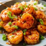 Close-up of glistening High-Protein Honey Garlic Shrimp served with white rice and garnished with green onions.