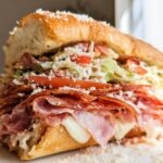 A delicious Italian Grinder Salad Sandwich overflowing with meats, cheese, lettuce, tomatoes, and dressing.