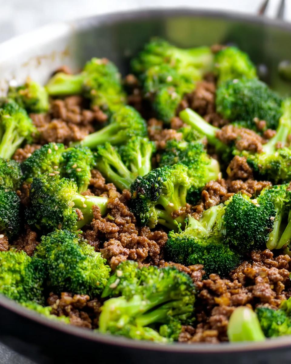 Close-up of a Keto Hamburger Broccoli Skillet in a pan, showing seasoned ground beef mixed with vibrant green broccoli florets and sesame seeds.