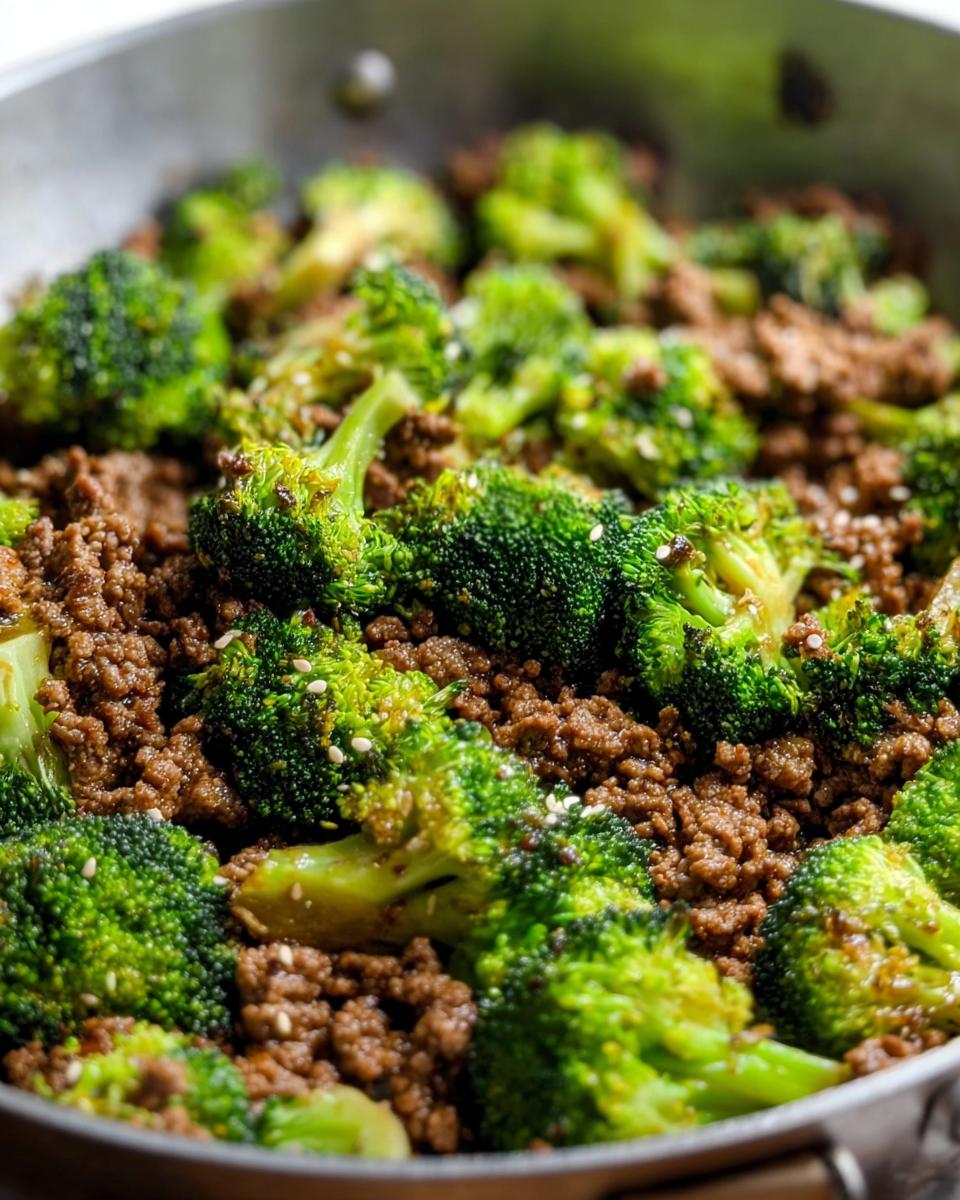 Close-up of a Keto Hamburger Broccoli Skillet in a pan, featuring seasoned ground beef and tender broccoli florets sprinkled with sesame seeds.