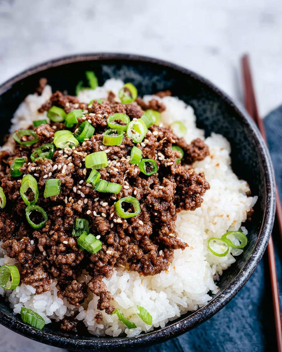 A close-up of a Korean Ground Beef Bowl, featuring seasoned ground beef over white rice, garnished with chopped green onions and sesame seeds.