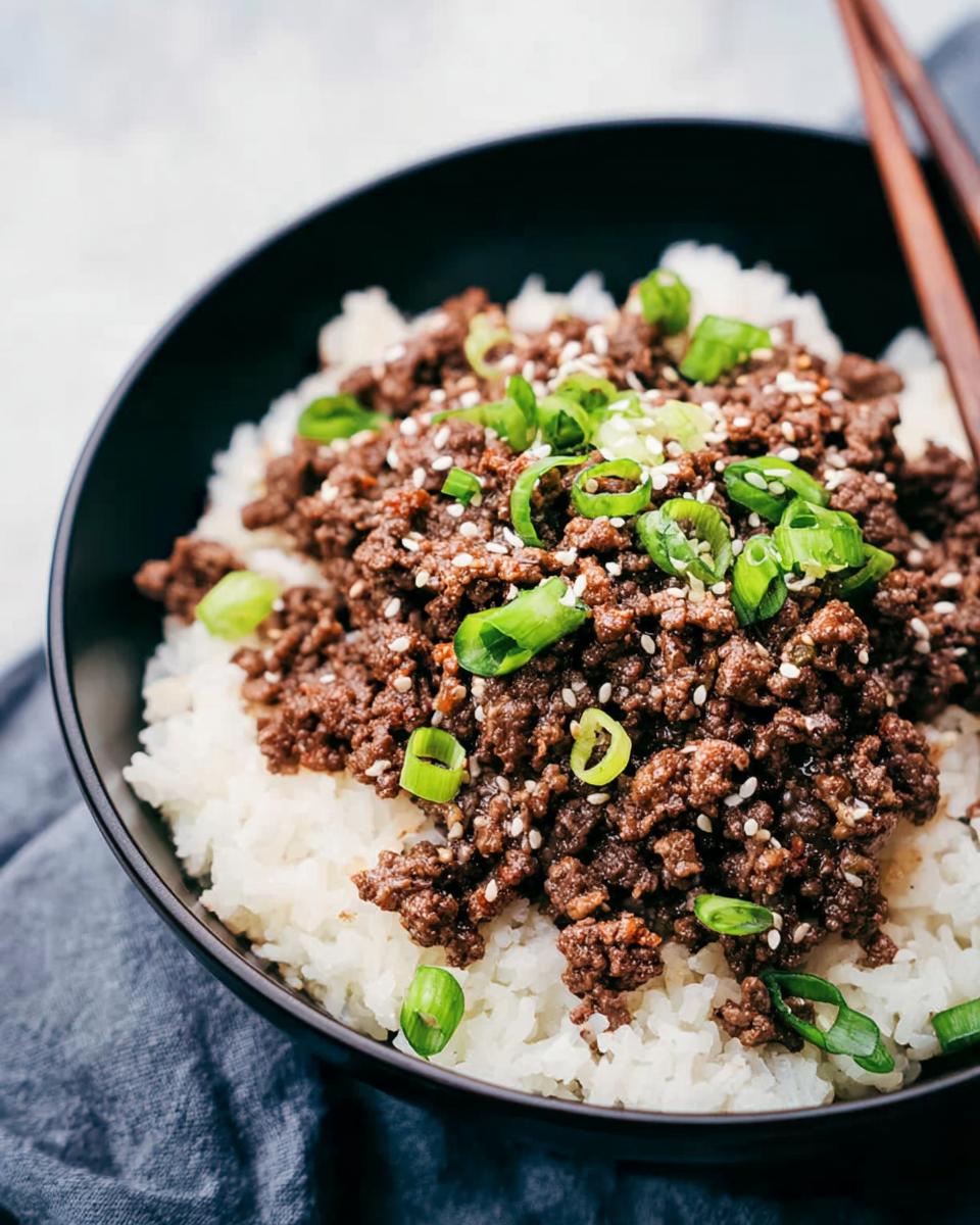 A close-up of a Korean Ground Beef Bowl, featuring seasoned ground beef over white rice, topped with green onions and sesame seeds.