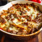 A baked Low Carb Philly Cheesesteak Casserole in a baking dish, topped with melted cheese and parsley.