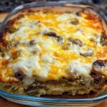 A freshly baked Low Carb Philly Cheesesteak Casserole in a glass dish, topped with melted cheese, peppers, and mushrooms.