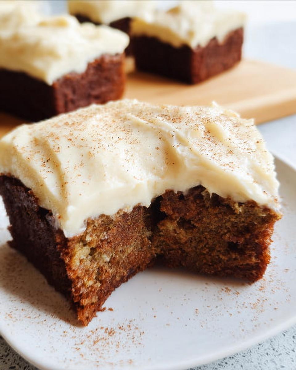 Close-up of a slice of Banana Bread Brownies Made Easy, topped with creamy frosting and a dusting of cinnamon.