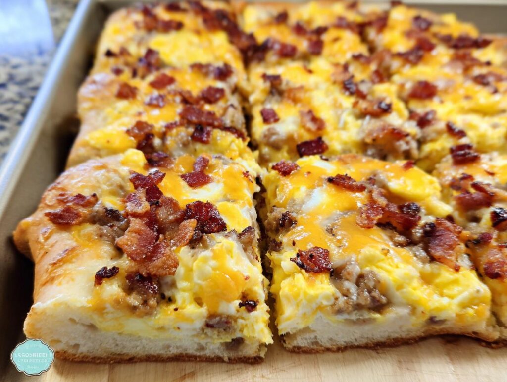 Close-up of a slice of breakfast pizza egg recipe topped with scrambled eggs, cheese, and crispy bacon.