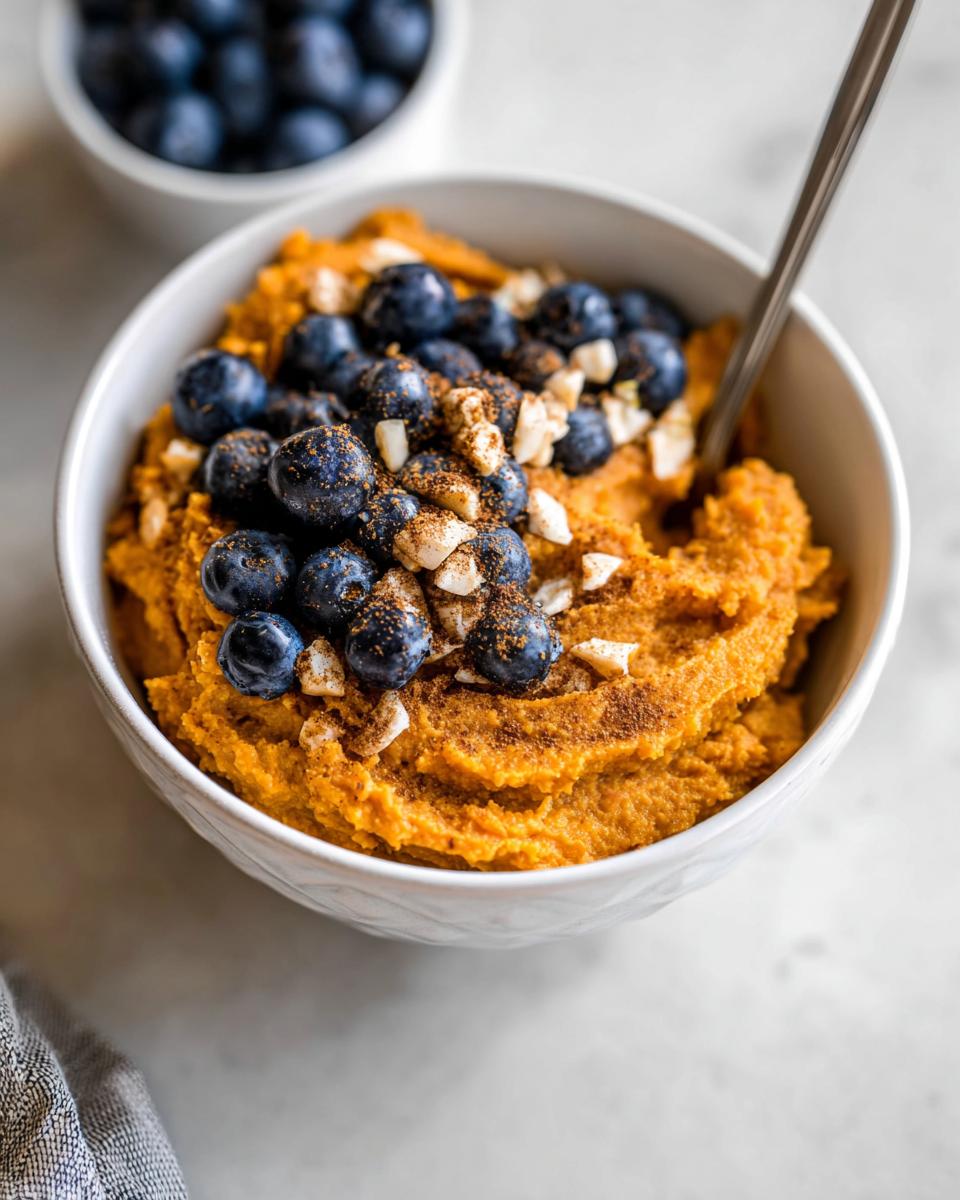 A Delicious Sweet Potato Breakfast Bowl topped with fresh blueberries, chopped nuts, and cinnamon.