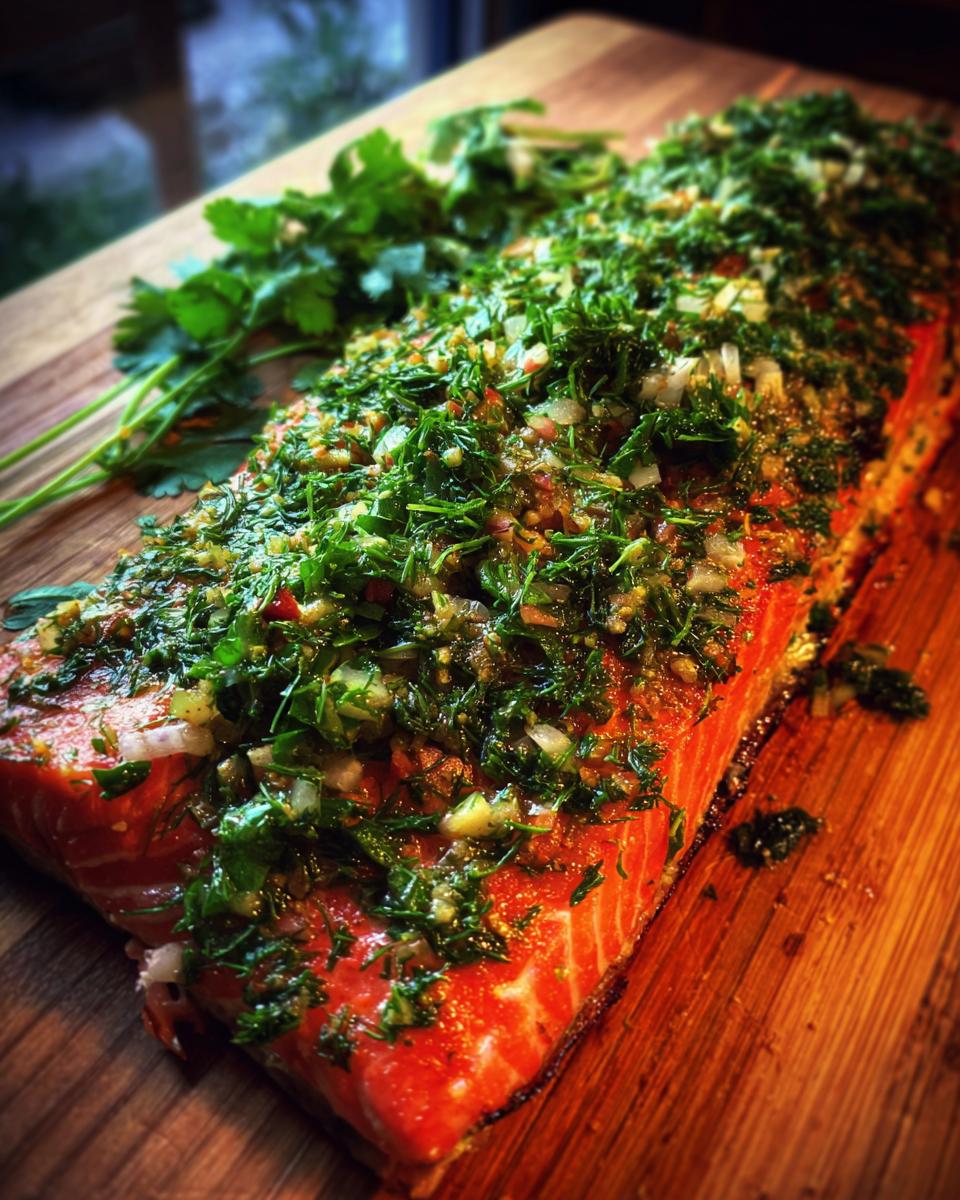 A whole salmon fillet seasoned with fresh herbs and spices, ready for grilling on a cedar plank.