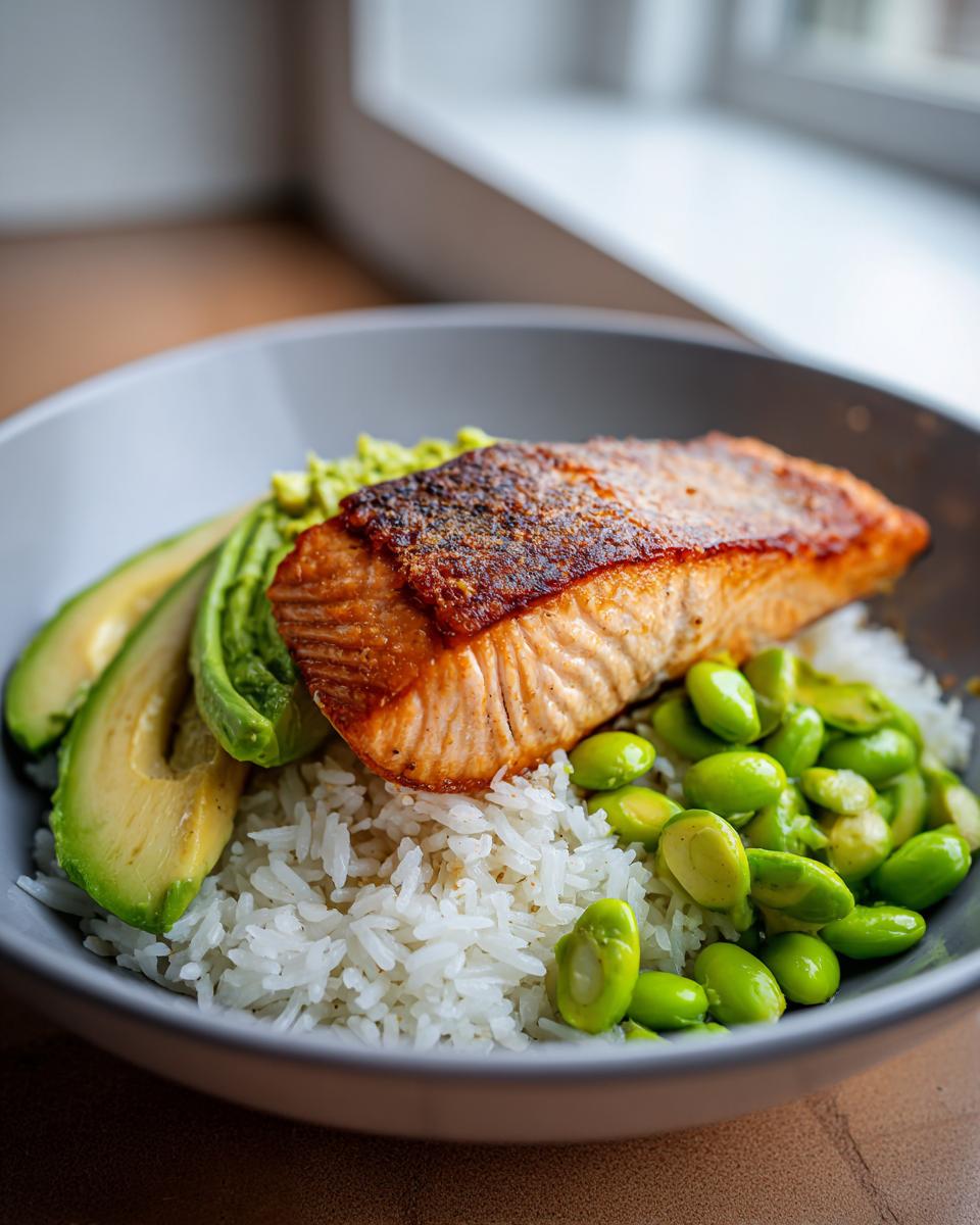 A close-up of a Crispy Salmon and Rice Bowl with sliced avocado and edamame.